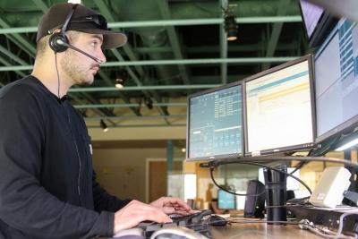 Man sitting in front of three computer monitors with a headset on answering 911 calls